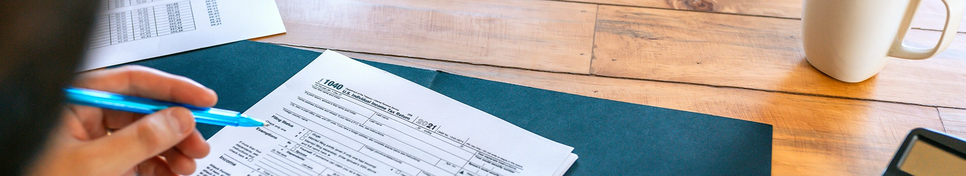 Vue de dessus d’un bureau d’entreprise avec ordinateur portable, calculatrices, carnets et documents financiers, symbolisant la préparation des impôts et acomptes