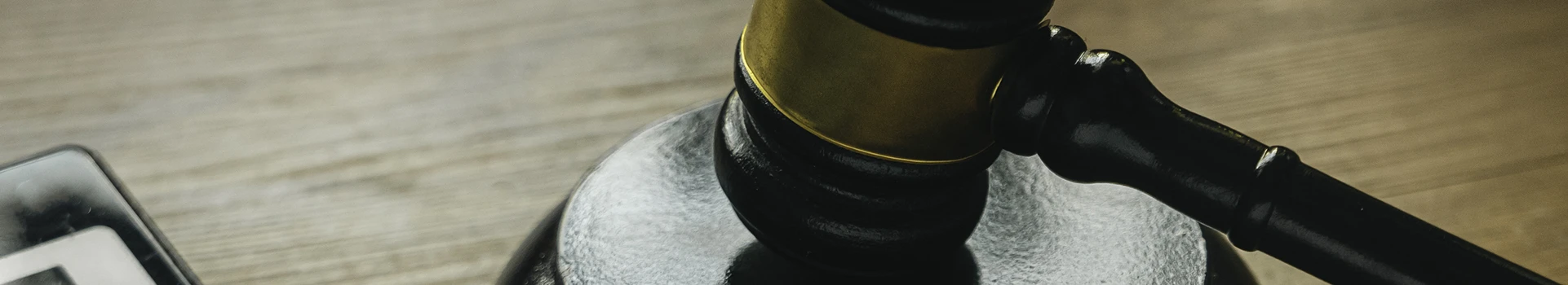 Marteau de justice posé à côté d’une calculatrice sur un bureau, illustrant les sanctions financières en entreprise